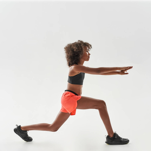 Athletic curly african girl doing lunges exercise - Фото, зображення