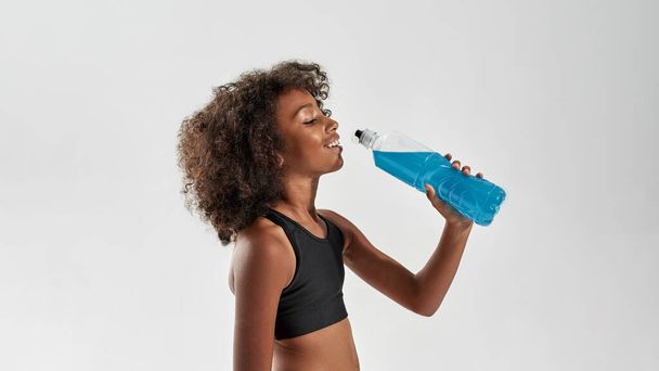 Athletic black girl drink sport drink from bottle - Foto, Imagem