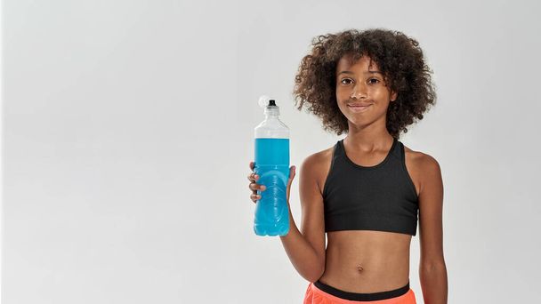Smiling black girl with bottle of blue sport drink - Foto, afbeelding