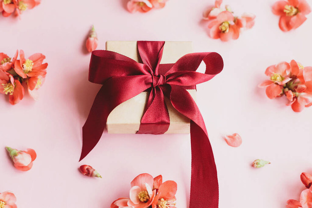 Stylowe pudełko z kwiatami na różowym tle kompozycji. Szczęśliwego Dnia Matki. Szablon karty okolicznościowej. Zrób prezent ze wstążką i czerwonymi kwiatami. Sztandar urodzinowy lub Dzień Kobiet - Zdjęcie, obraz