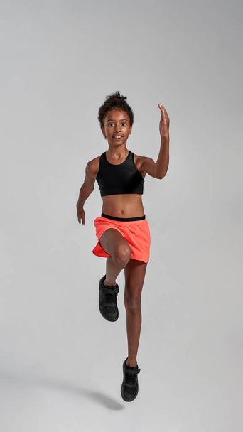 Front view of smiling athletic black girl running - Fotó, kép