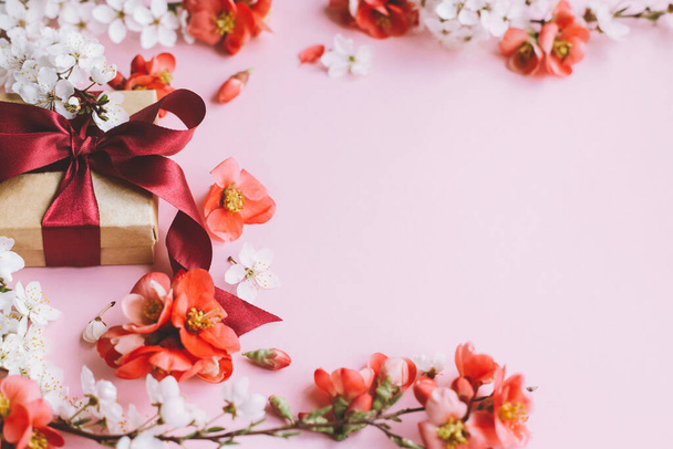 Šťastný Den matek. Stylová dárková krabice s květinami na růžovém pozadí. Šablona blahopřání s prostorem pro text. Řemeslný dárek s stuhou, červenými květy a třešňovými květy. Pohlednice - Den žen - Fotografie, Obrázek