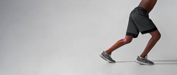 Run black boy with medical plasters on injured leg - Фото, зображення