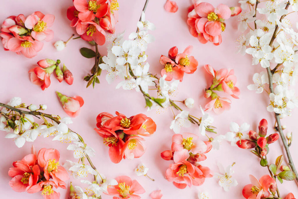 Élégante composition de fleurs printanières sur fond rose à plat. Fleurs rouges et fleurs de cerisier disposition. Bonjour Spring. Modèle de carte de vœux floral. Joyeuses Pâques - Photo, image