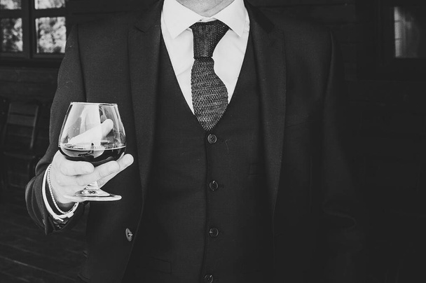 Close up of man hold glass of whiskey, drink alcoholic beverage in the pub. Business man drinking brandy. Black and white photo. - Foto, imagen