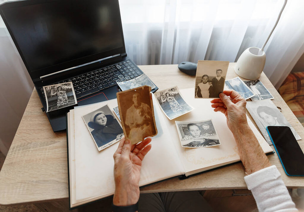 Eski eller. Kıdemli kadın 1955, 1957,1967 'de çekilmiş kendi fotoğraflarını arıyor. Emekli insan ne kadar genç olduğunu hatırlarken gülümser. Seçici odak.  - Fotoğraf, Görsel