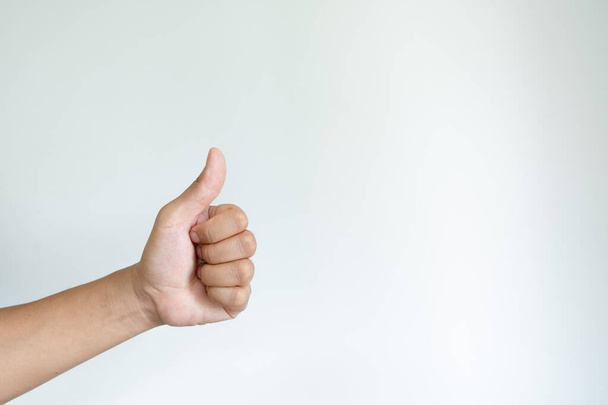 Closeup of asian male left hand showing thumbs up sign on white background - Фото, изображение