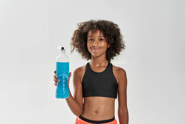 Black girl hold opened bottle of blue sport drink - Fotografie, Obrázek
