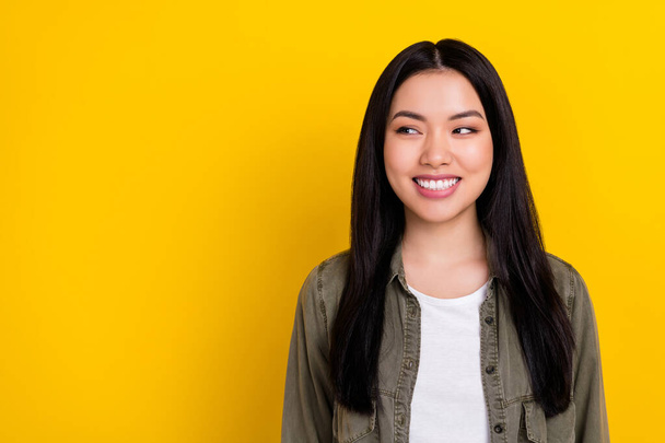 Photo of impressed millennial brunette lady look promo wear khaki shirt isolated on yellow color background - Foto, afbeelding