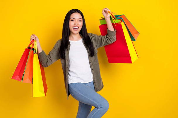 Photo of funky millennial brunette lady hold bags yell wear casual cloth isolated on yellow color background - Fotoğraf, Görsel