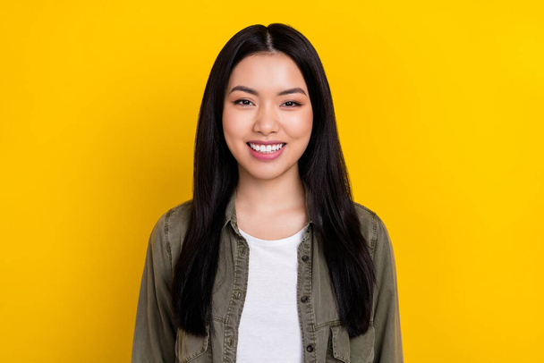 Portrait of young cheerful beaming korean ethnicity female wear khaki jacket isolated on yellow color background - Valokuva, kuva