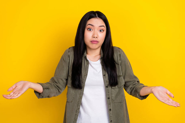 Photo of serious millennial brunette lady shrug shoulders wear khaki shirt isolated on yellow color background - Foto, Bild