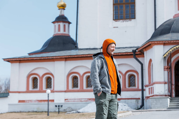 Ein Mann auf einem Ausflug in ein altes Kloster. Tourist sieht die Sehenswürdigkeiten an einem Frühlingstag - Foto, Bild