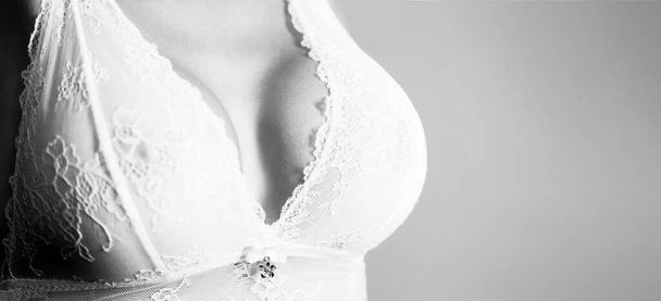 Plastic surgery. Sexy boob. Close up of breast of girl presenting her bra. Closeup of sexy female boob in white bra. Sensual women, huge breasts, big boobs. Sexy sensual girl - Photo, image