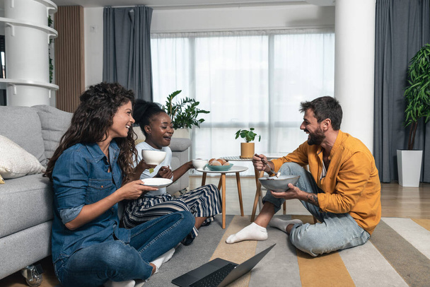 Group of young creative successful friends sitting on the floor of their modern home office apartment taking a break from freelancer work. Self-employed people man and women chilling together - Fotoğraf, Görsel