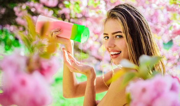 Smiling woman with bottle of shampoo, balm or conditioner. Herbal SPA. Organic cosmetics for hair. - Photo, Image