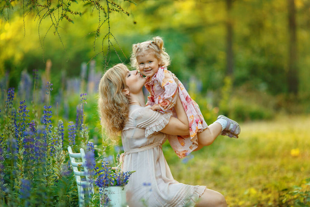 Mother and daughter in spring garden. Happy woman and child in the blooming spring garden. Mother kissing baby. Mothers day holiday concept  - Photo, Image