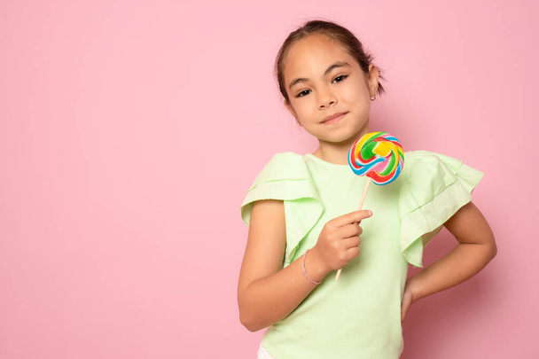 beautiful cute little girl eating lollipop standing isolated over pink background. - Fotó, kép