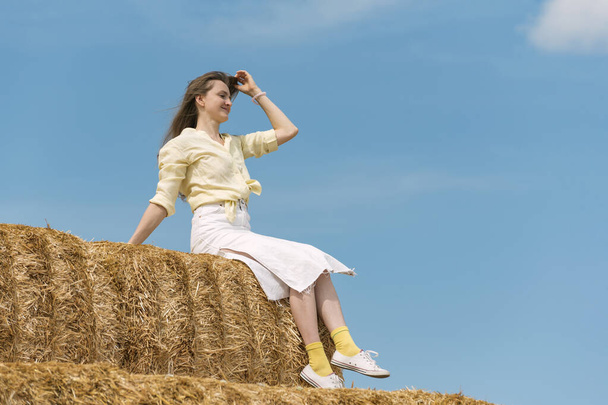 Pretty lady sits on straw and poses for photo. Weekend in the countryside. Summer day - Foto, Imagem