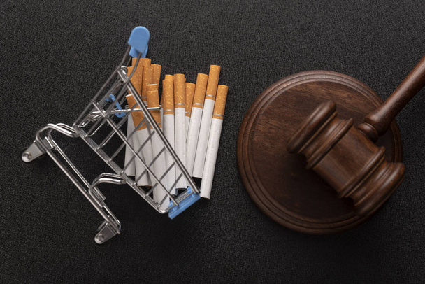 Giudice di legno martelletto vicino sigaretta nel carrello della spesa vista dall'alto primo piano su sfondo nero. Diritto del tabacco - Foto, immagini