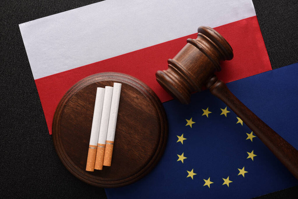 Papierosy i młotek sędziego na tle flagi Polski i Unii Europejskiej. Nielegalny handel papierosami między Polską a krajami UE - Zdjęcie, obraz