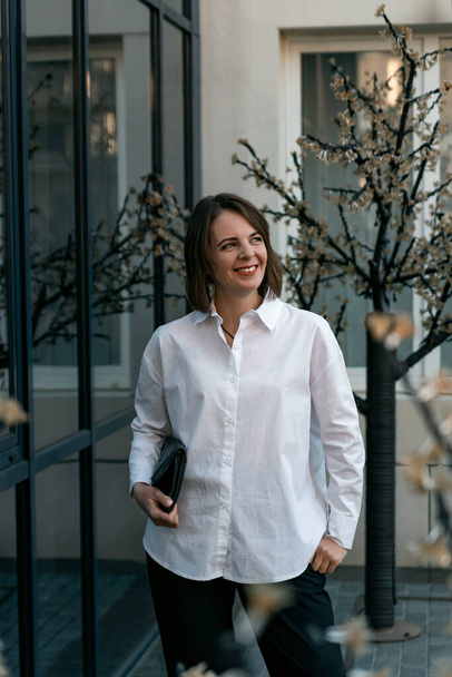 Portrait of successful young woman in white shirt and black trousers. Business woman in semi-casual - Foto, Imagem
