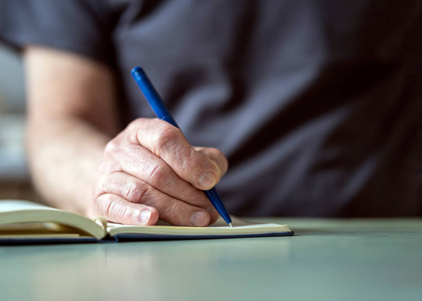mannelijke hand schrijven met pen op zijn notebook. - Foto, afbeelding