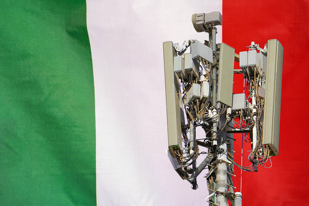 Telecommunications tower with a 5G cellular network antenna agains flag of Italy. Telecommunication tower of 5G cellular communication. 5G technology usage on telecommunications towers in Italy - Foto, Imagen