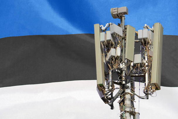 Telecomunicações torre com uma antena de rede celular 5G agains bandeira da Estónia. Torre de telecomunicações de comunicação celular 5G. Utilização da tecnologia 5G em torres de telecomunicações na Estónia - Foto, Imagem