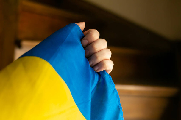 mano con pequeña bandera ucraniana escaleras de madera fondo - Foto, imagen
