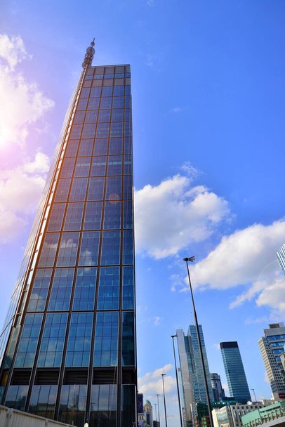 Prachtig stadslandschap, verlicht door de zon lucht tegen het silhouet van wolkenkrabber gebouw in de Europese stad. Uitzicht op hoog glas en staal hoogbouw. - Foto, afbeelding