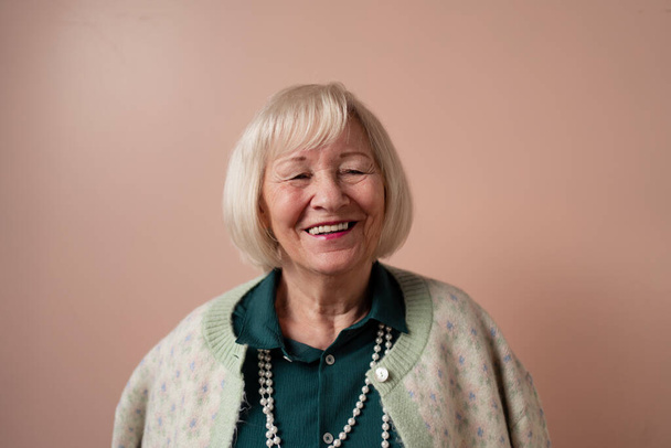 Smiling elegant elderly woman on pink color background, studio portrait - Foto, Imagen