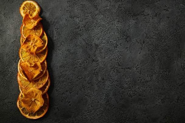 Dried fruits, dried orange slices, dried persimmon slices on a dark textured background. - Fotografie, Obrázek