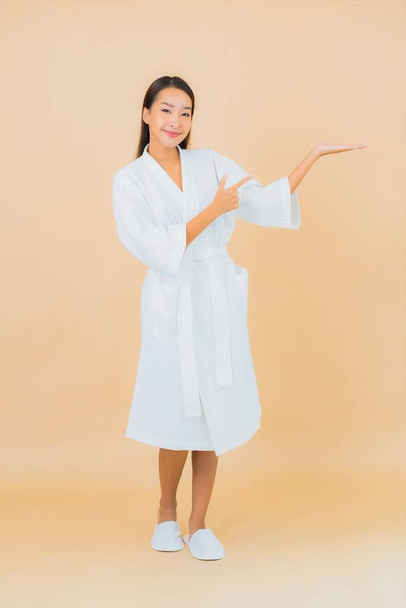 Портрет красива молода азіатка носить халат з посмішкою на кольоровому фоні
 - Фото, зображення