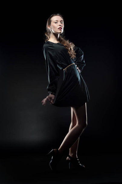 Beautiful sexy brunette girl posing on a black background in an evening dress - 写真・画像