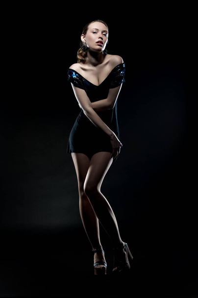 Beautiful sexy brunette girl posing on a black background in an evening dress - Фото, зображення