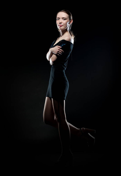Beautiful sexy brunette girl posing on a black background in an evening dress - Foto, Bild