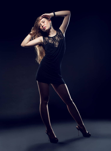 Beautiful sexy brunette girl posing on a black background in an evening dress - Fotoğraf, Görsel