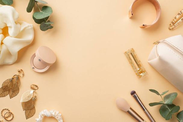 Beauty concept. Top view photo of gold leaf shaped earrings wristlet rings eyeshadow makeup brushes cosmetic bag scrunchy barrettes and eucalyptus on isolated pastel beige background with copyspace - Photo, Image