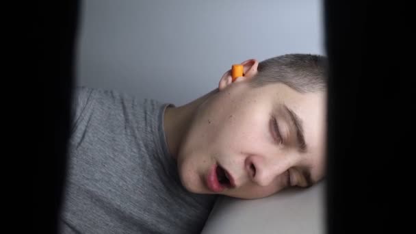 Ten chlap si nasadil špunty do uší. Detailní záběr oranžové protihlukové bariéry. hluboký spánek. Lékař ENT doporučuje pomerančové chrániče sluchu snížit okolní hluk. Zvýšená citlivost na zvuky. - Záběry, video