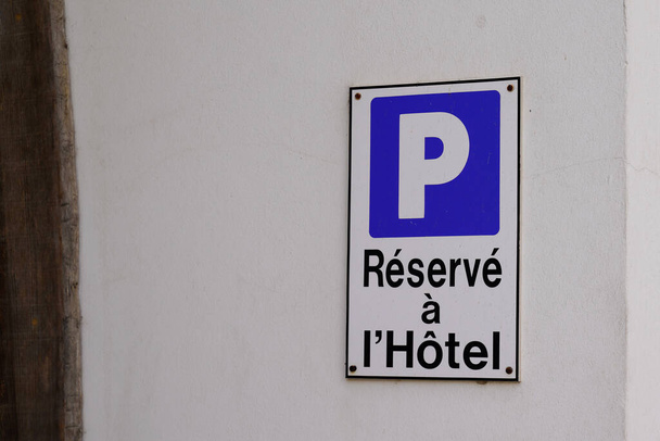 Hotel parking sign with french text means parked car is reserved hostel on wall city building facade - Foto, Imagen