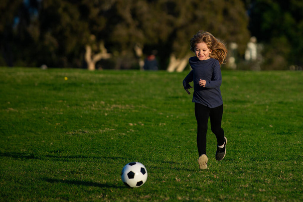 Soccer kid boy playing football. Child boy play football on outdoor field. Boy kicking football ball. - Zdjęcie, obraz