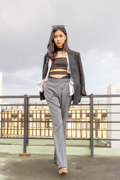 Fashionable concept, Fashion woman posing on rooftop while wearing gray pants with white shirt. - Фото, изображение