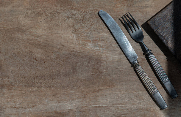 Vintage old metal knife with fork on old rustic wooden background. Eating concept, Copy space, Selective Focus. - Photo, Image