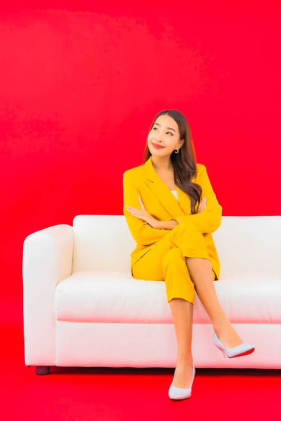 retrato bonito jovem asiático mulher sentar no sofá cadeira no vermelho fundo - Foto, Imagem