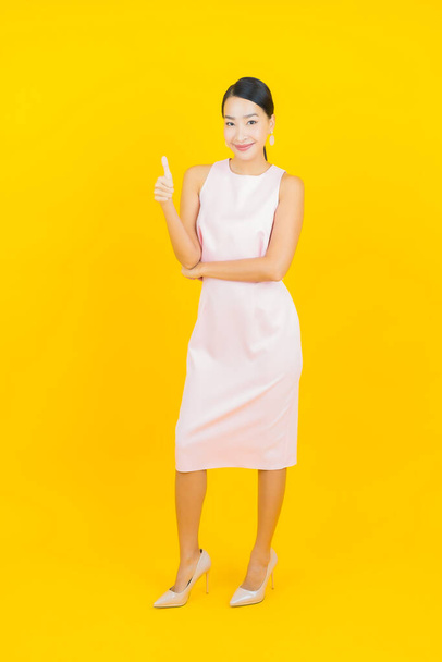 Portrait beautiful young asian woman smile with action on yellow color background - Fotó, kép