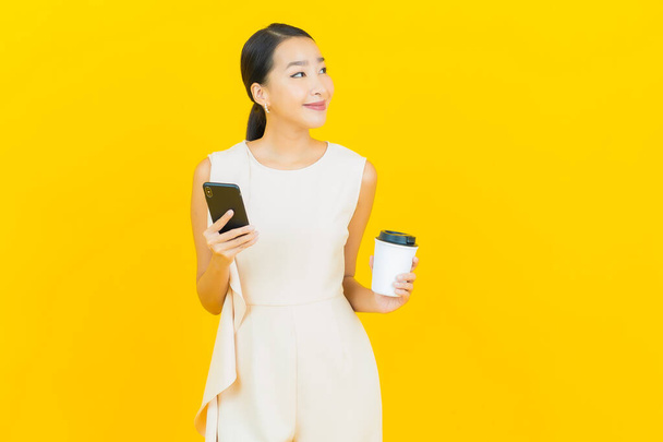 Retrato bonito jovem asiático mulher sorriso com telefone celular inteligente na cor amarela fundo - Foto, Imagem