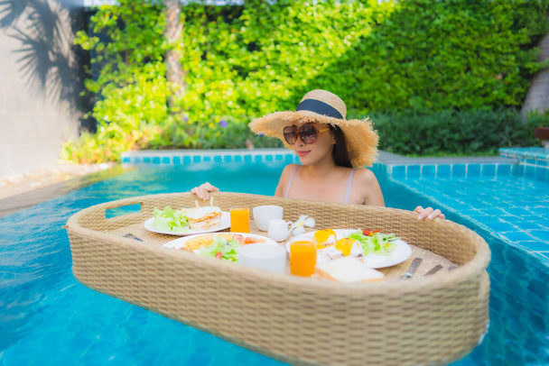 Портрет молодої азіатки щаслива усмішка насолоджується плаваючим сніданком у басейні в готельному комплексі
 - Фото, зображення