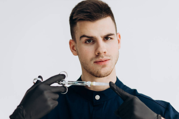 Male doctor in black clothes and gloves holding syringe - Fotó, kép