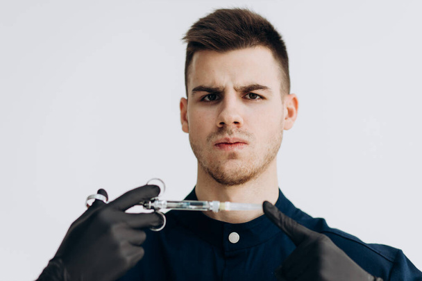 Male doctor in black clothes and gloves holding syringe - Fotoğraf, Görsel